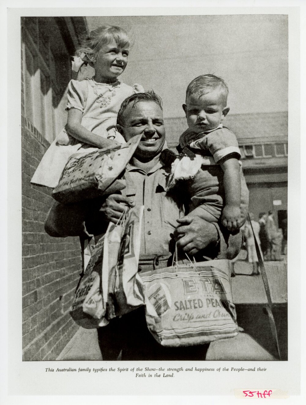 Father carrying children with showbags, 1951