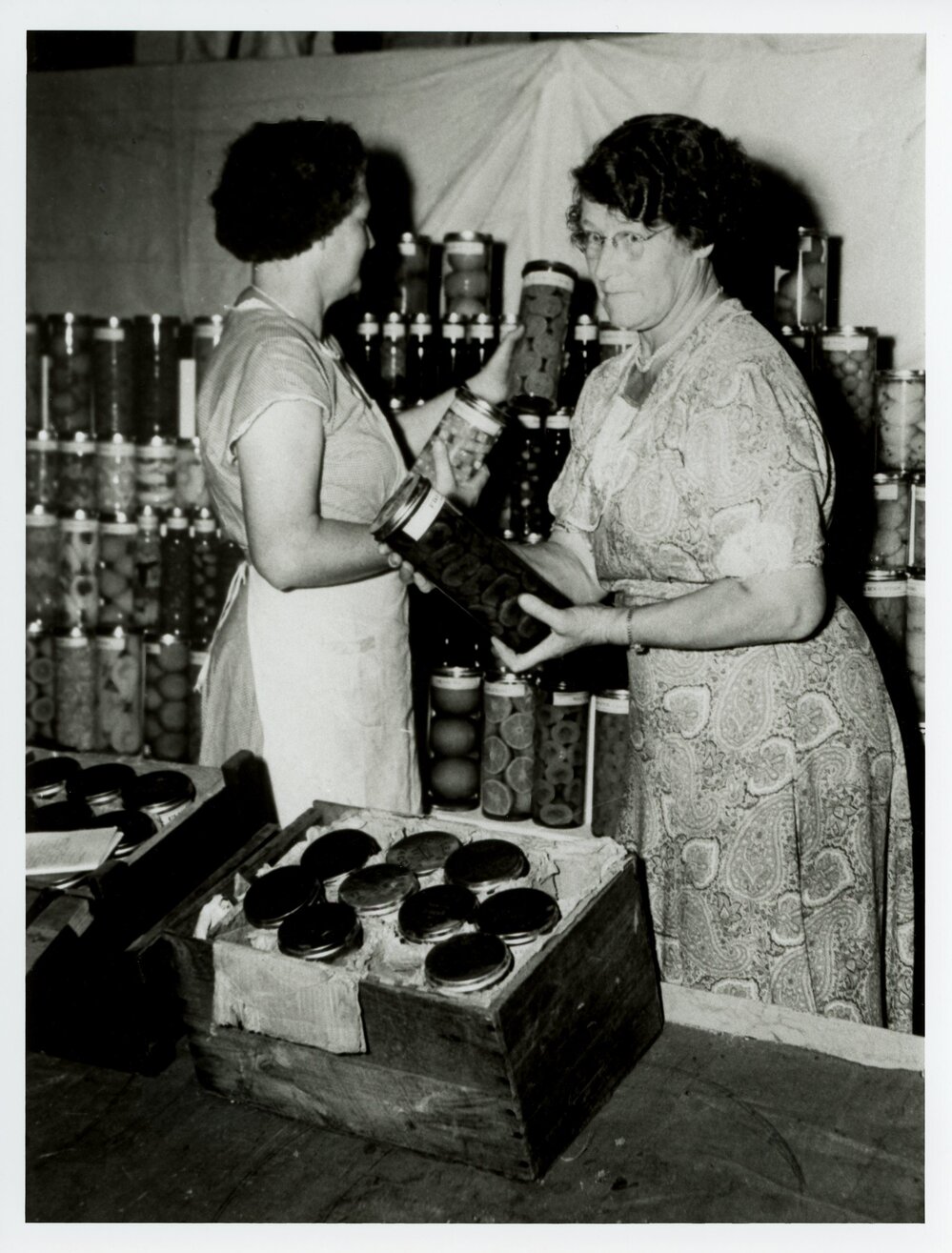 Two Women Unpacking Preserves for District Exhibit Display, 1955